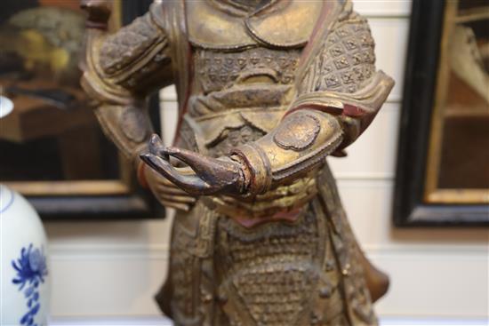 A large Chinese gilt-decorated and polychrome lacquer figure of a temple guardian, 19th century, H.75cm, losses